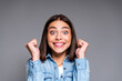 © deagreez - Excited young woman celebrating with clenched fists and big smile in denim shirt — joyful studio portrait conveying happiness, enthusiasm, success and positive emotion