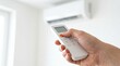 © Gophotograph - Energy saving concept showing a hand turning off the air conditioning unit with a remote.