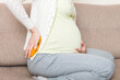 © sosiukin - Pregnant woman suffer from back pain holds a hot bottle or warmer against her back. Concept pregnant woman lifestyle and health care