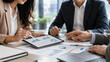 © Rachel - Business professionals analyzing tablet dashboard and paper charts