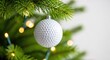 © Chanchai - A white dimpled golf ball ornament hangs from a lush green pine branch, surrounded by soft glowing holiday lights and festive winter bokeh, craft, hobby, bauble