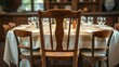 © MOMO - Empty wooden chair pulled away from a fully set dining table.