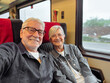 © luciano - Happy senior couple traveling by train enjoying a relaxing journey and retirement vacation