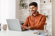 © Prostock-studio - Smiling Young Caucasian Man Sitting At Desk Using Laptop In Modern Home Office. Focused On Work And Enjoying Productive Moment In Comfortable Environment, Promoting Business Concept.