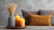 © Sampao - Cozy living room decor with decorative candles, a stylish vase of dried grasses, and soft pillows creating a warm and inviting atmosphere for relaxation