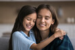 © fizkes - Close up shot loving mother and cute daughter hugging, enjoy moment of tenderness and warmth with eyes closed sit on sofa spend time together, having good friendly relations. Family ties, motherhood