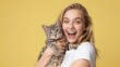 © Volha - Woman holding kitten and smiling on yellow background