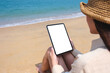 © Farknot Architect - Mockup image of a woman holding a digital tablet with blank desktop screen while sitting on the beach by the sea