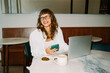 © Julia - Young business person working remotely with coffee and laptop