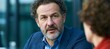 © Ilja - Middle aged man with a beard having a serious business conversation in a light modern office space