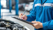 © KotBaton - Professional auto mechanic writing inspection notes on a clipboard during vehicle diagnostics. Automotive maintenance, repair service and quality control concept.