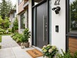 © World Art 2.0 - Modern dark grey front door featuring a sleek silver handle with a smart video doorbell and motion sensor security light mounted on the white stucco exterior wall of a house