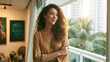 © CreativeArt - Woman standing on her modern apartment balcony, smiling while looking towards the city view and warm sunset light