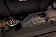 © Terence - Close-up of a car radiator pressure cap with yellow warning labels, connected to a coolant reservoir tank inside a modern vehicle's engine bay