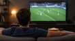 © Rhony - Young man watching soccer game on big television screen at home.
