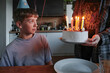 © Danil Nevsky/Stocksy - Boy receiving birthday cake with lit candles and party hat