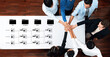 © InfiniteFlow - A top view of a diverse group of professionals collaborating on project tasks. The image highlights teamwork with hands together over a table, surrounded by workflow diagrams. Trope