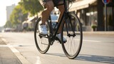 Man riding a black bicycle on a city street, close-up on legs and wheels.