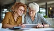 © Sutopo - Young woman and elderly mentor reviewing financial data on a digital tablet in a office setting