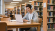 © patricia - Smiling Young Man Studying on Laptop in Library with Headphones
