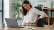 © olga_demina - A woman at her home workstation experiences physical discomfort and back pain, demonstrating the need for ergonomics and health care during long work hours