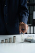 © Wanda - Businessman with coin stacking and hourglass on table, investment and time concept
