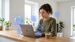 © Jing - Young woman working remotely on laptop at home, surrounded by floating holographic icons representing cloud upload, calendar schedule and analytics charts