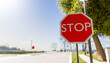 © Connect Images - Red octagonal stop sign on a sunny rural road with trees and clear sky.