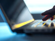 © Connect Images - Fingers touch glowing keyboard of a laptop in a dimly lit room.