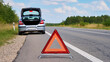 © Creative  - Car breakdown on rural highway, Emergency warning triangle on asphalt, Broken car with open hood, Roadside assistance concept, Vehicle failure on country road, Emergency stop on roadside