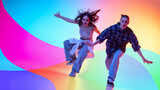 Two female dancers moving in colorful neon studio with abstract background. Concept of dance crew, youth lifestyle, music promotion, street fashion, and creative advertising.
