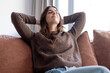 © luciano - Woman relaxing at home with eyes closed, enjoying peace and tranquility on a comfortable sofa