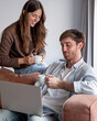 © luciano - Young couple working together on a laptop, enjoying coffee while brainstorming, communicating, and connecting