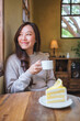 © Farknot Architect - Vertical portrait image of a woman drinking coffee and eating a lemon cake in cafe
