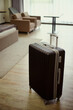 © DragonImages - Vertical shot of rolling suitcase standing in hotel room, suggesting family travel check in or vacation stay. Ideal for tourism marketing, hospitality booking, travel service promotion