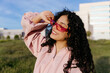 © Tania Cervian/Stocksy - Woman in pink sunglasses smiling outdoors