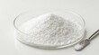 © Velora - A pile of white powder in a glass petri dish with a metal spatula for scientific or medical research. allantoin