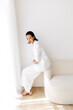 © Tania Cervian/Stocksy - Elegant woman posing in white suit on sofa
