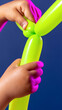 © sabyna75 - Child creating neon balloon art with bright green balloons on blue background