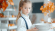© Ruzana - Young caucasian girl holding plates in bright kitchen with autumn decor