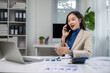 © apichat - Businesswoman talking on phone working in office