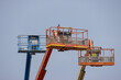 © Rattanachat - Three aerial work platforms elevated against bright blue sky