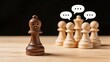 © Prime - Sad lonely wooden chess pawn piece standing alone separated from group with speech bubbles, representing bullying isolation exclusion or social anxiety concept.