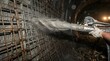 © DreamGen Works - Industrial shotcrete application in tunnel construction, worker spraying liquid concrete on steel reinforcement, underground civil engineering project