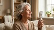 © Olga Ко - Happy senior woman relaxing on sofa and cooling herself with a portable handheld mini fan. Elderly female finding relief from summer heat or menopause hot flush at home