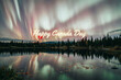 © HomesGraphics - Happy Canada Day greeting text over northern lights, aurora borealis reflecting in calm lake water, scenic Canadian wilderness landscape at night