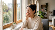 © Angavlan - Woman covers mouth during yawn near window, experiencing morning fatigue in cozy home. Female with coffee mug, clearly tired, showing deep yawn near window. Daily life concept for wellness,