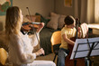 © DragonImages - Caucasian woman teaching girl playing violin and cello while studying sheet music at home, supporting music education and creative skill development. Ideal for lesson ads or school promotion