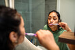 © Marko Geber - Young woman brushing teeth in home bathroom