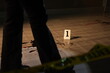 © ultramansk - A bloodstained knife lies beside numbered evidence markers and blood spatter on a dark floor at a crime scene murder investigation.